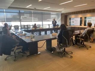 Dr. Michael Njo participating in a boardroom-style meeting with dental leaders seated around a conference table