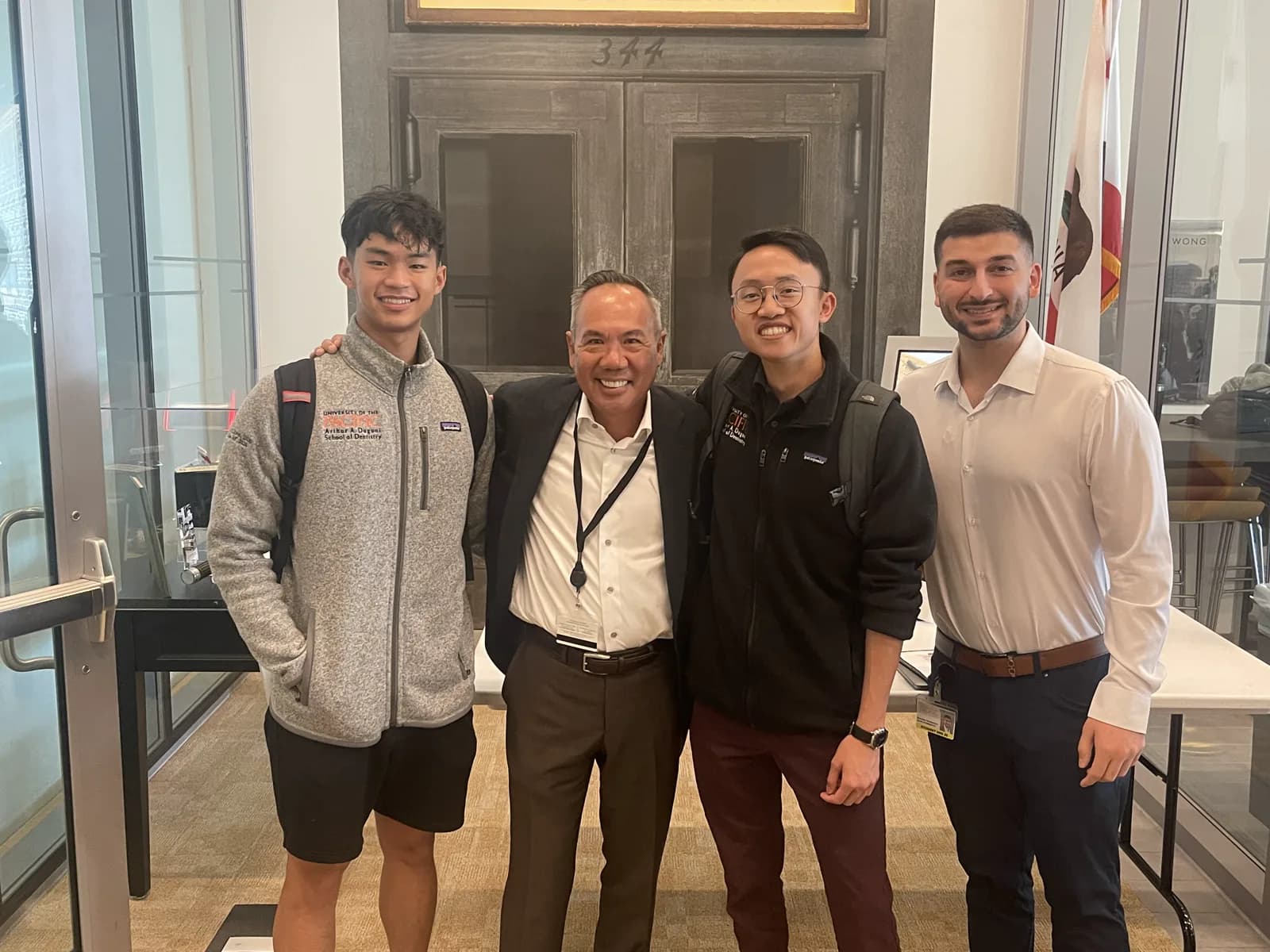 Dr. Michael Njo standing with three Dugoni Business Club student members inside the Arthur A. Dugoni School of Dentistry