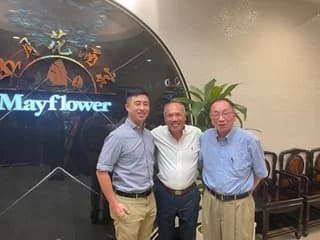Dr. Michael Njo standing with two colleagues in front of a Mayflower sign