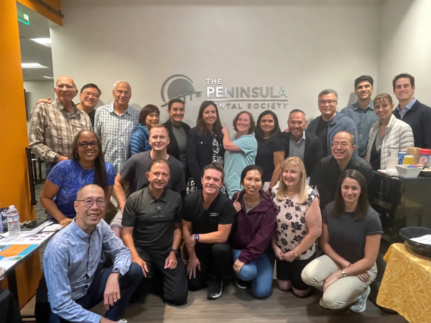 Group gathered in front of The Peninsula Dental Society wall sign