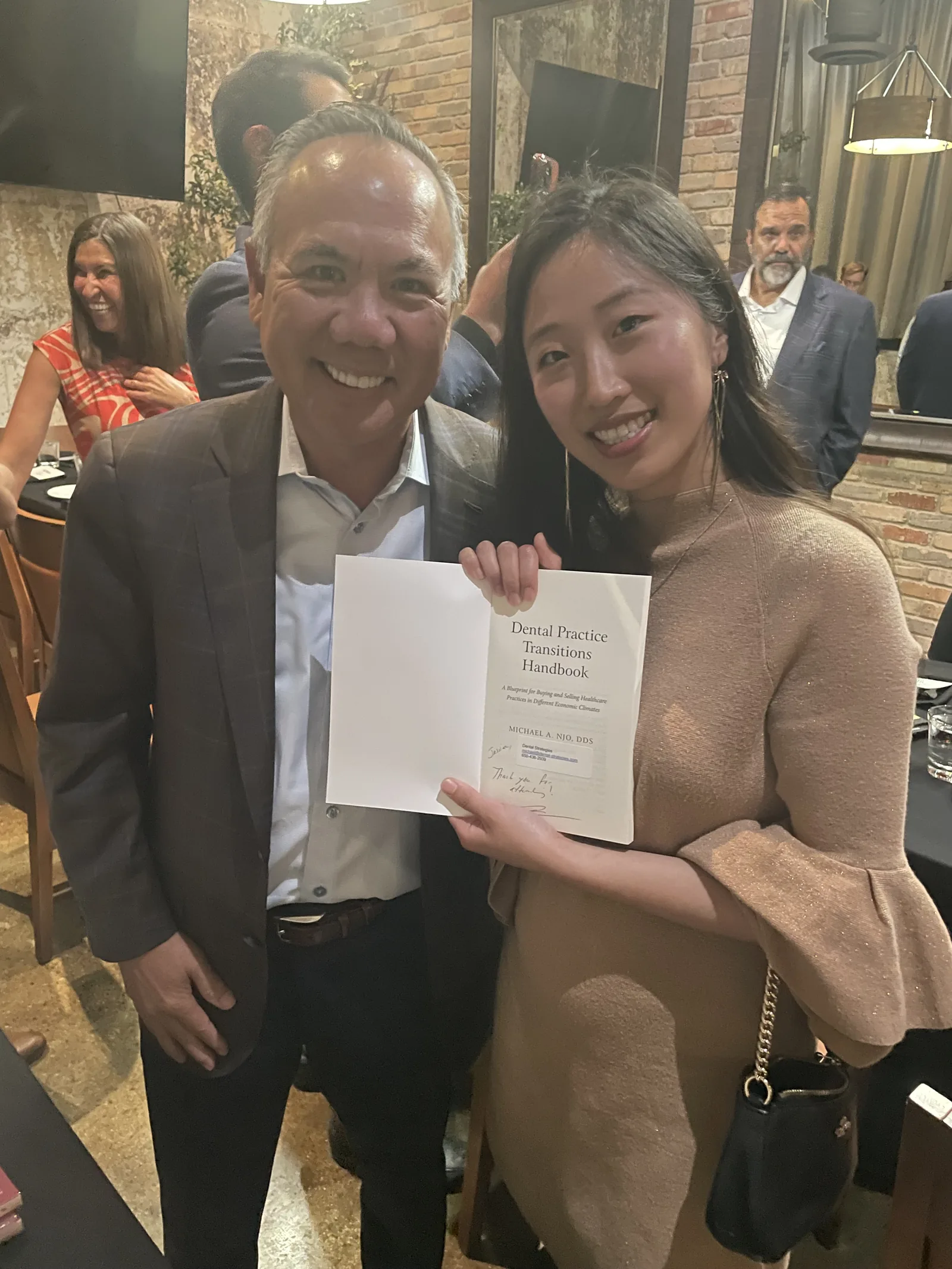 Dr. Michael Njo autographing Dental Practice Transitions Handbook at the Panel of Experts dinner