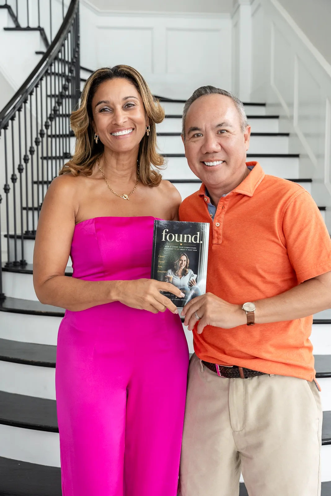 Dr. Michael Njo and Dr. Anissa Broussard holding a copy of her book FOUND on a staircase